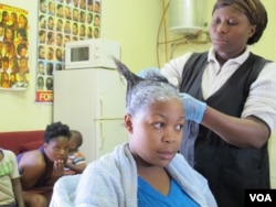 Kuaförde saçına düzleştirici uygulanan bir siyah kadın