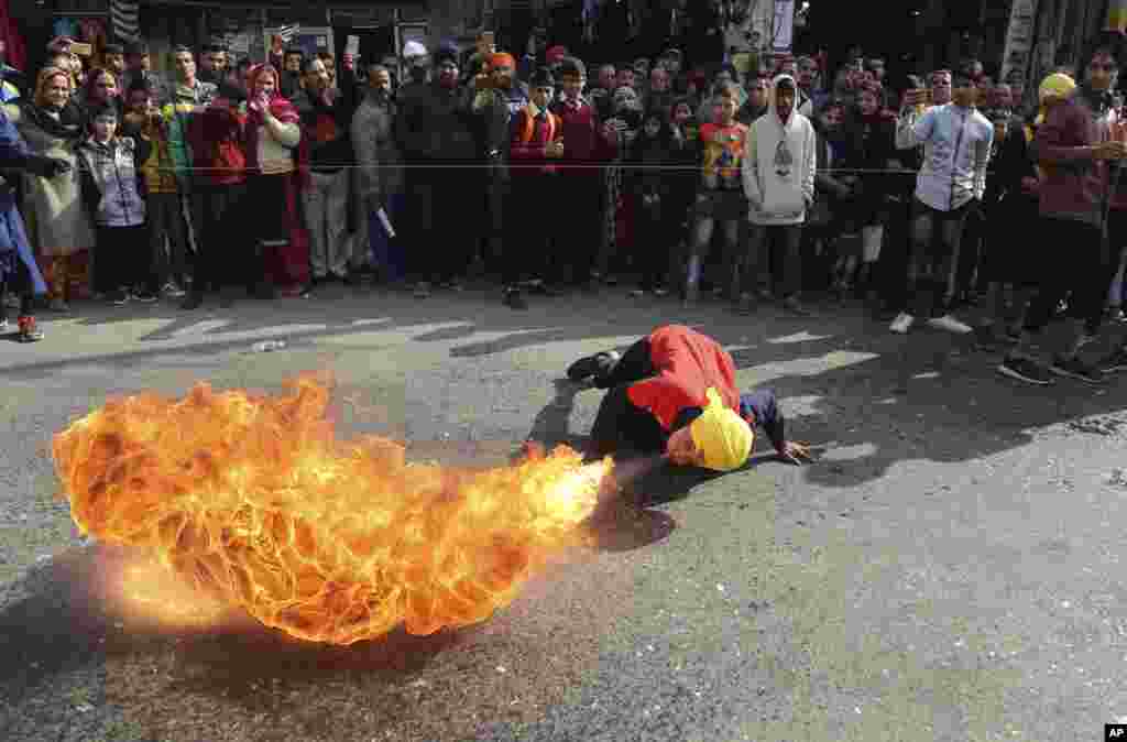 Bir Hint Sih savaşçı dini bir tören sırasında geleneksel dövüş sanatı yeteneklerini sergilerken ateşe üflüyor.