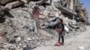 Gazze Şeridi'nin güneyindeki Refah'ta yıkılmış bir binanın enkazının yanından geçen bir kız çocuğu- 5 Nisan 2024.